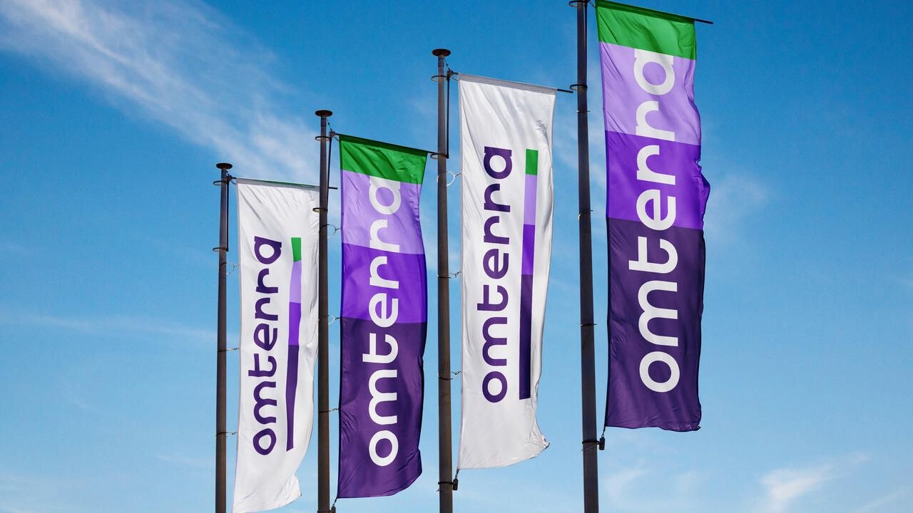 Omterra branded flags flying against a blue sky